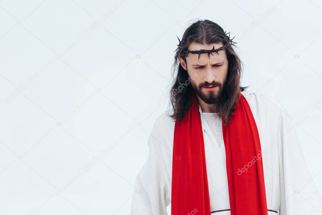 Jesus in robe, red sash and crown of thorns looking down against light sky