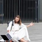 Irritated Jesus in robe and crown of thorns sitting on skateboard and gesturing to laptop with blank screen in city