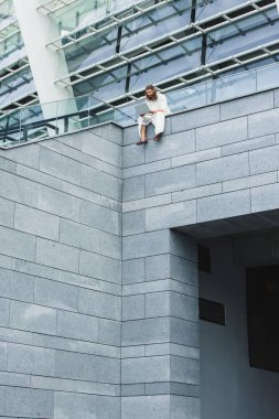 duvarda otururken dizüstü kullanarak İsa'nın düşük açılı görünüş