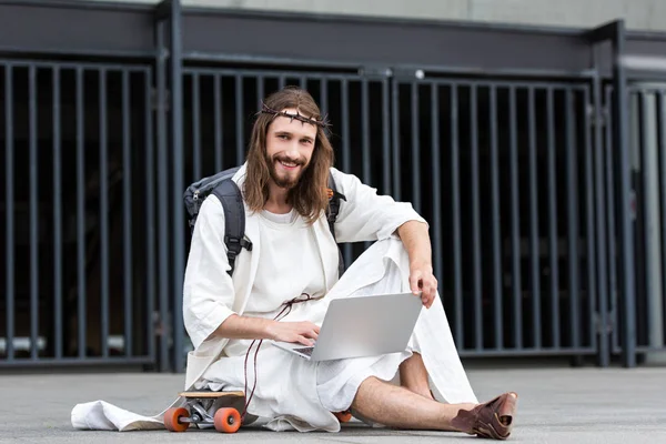 Heureux Jésus Robe Couronne Épines Assis Sur Skateboard Utilisant Ordinateur — Photo