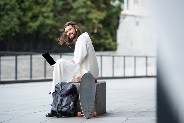 Smiling Jesus Robe Crown Thorns Sitting Stone Using Laptop Blank — Stock Photo, Image