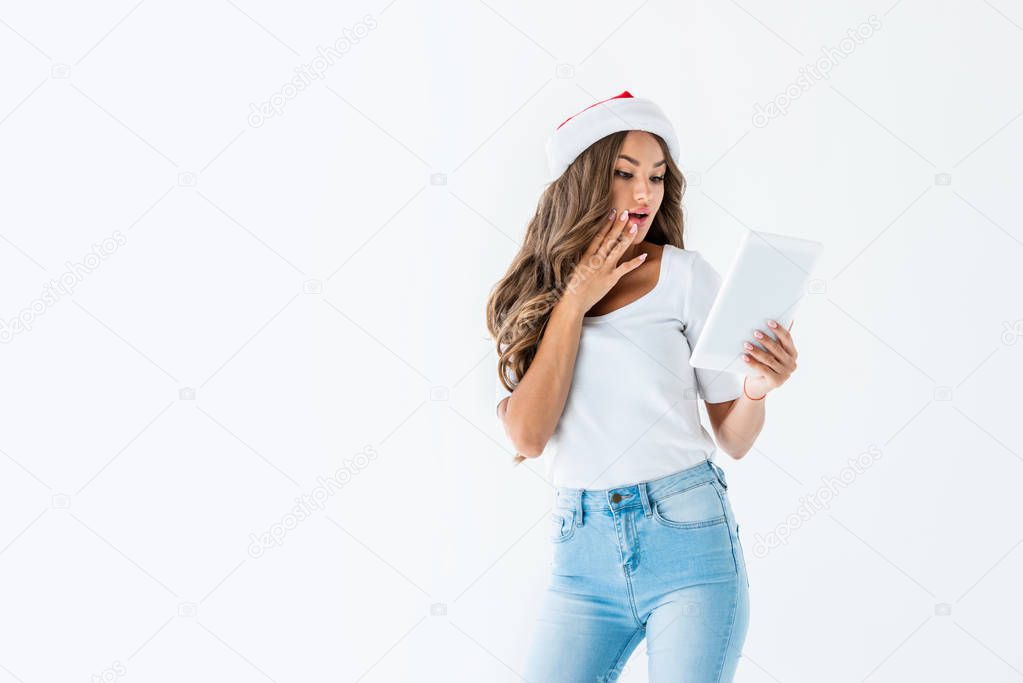 surprised girl in santa hat using digital tablet, isolated on white