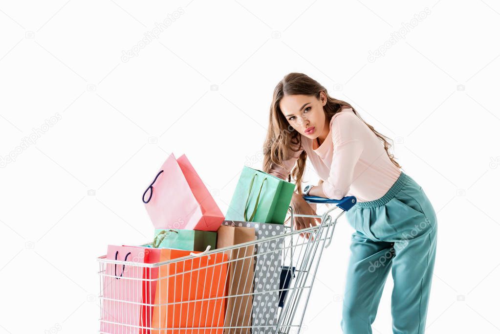 attractive tired girl with shopping cart and bags, isolated on white