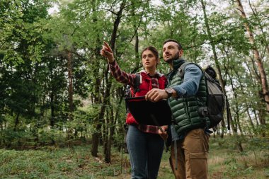 couple of travelers with map got lost in woods clipart