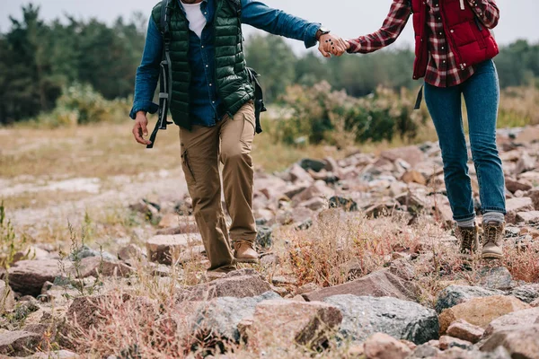 Teilansicht Von Wanderern Mit Rucksäcken Die Händchenhaltend Auf Steinen Gehen — Stockfoto