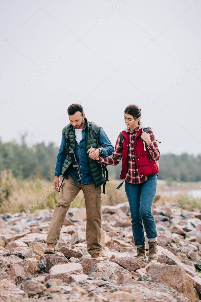hikers with backpacks walking on stones