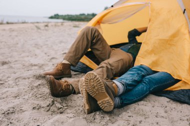 kumlu plajda kamp çadır içinde yatan çiftin kısmi görünümü