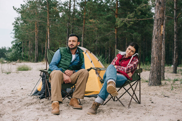 couple resting on chairs while having camping