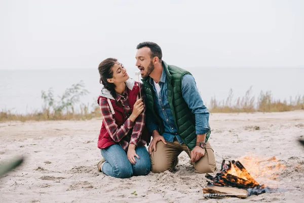 Woman Feeding Husband Marshmallow Campfire Sandy Beach — Free Stock Photo