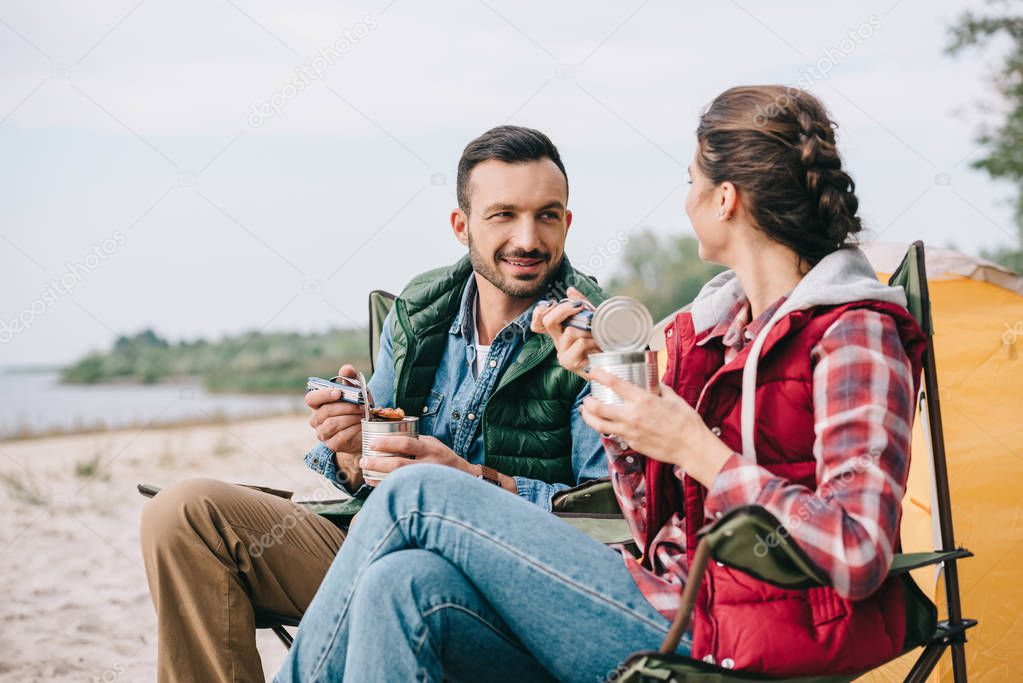 couple eating food from cans while having camping