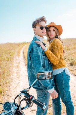 güzel çift ayakta retro motosiklet üzerinde çayır yakınındaki