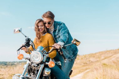 Genç çift kırsal çayır üzerinde vintage motosiklet üzerinde seyir