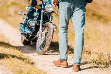 retro motosiklet yakınındaki izi boyunca yürüyen adam görünümünü kırpılmış