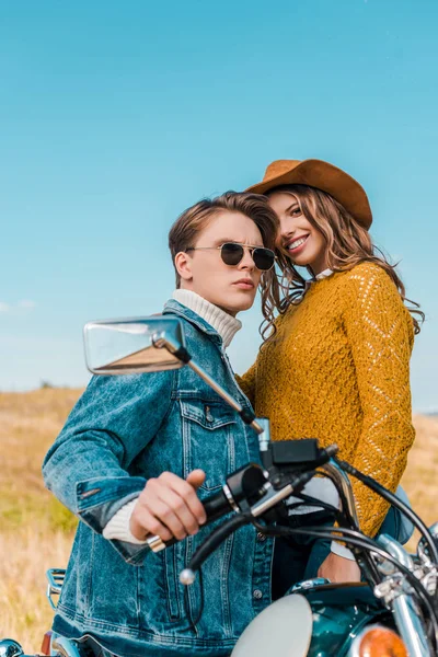 ハンサムな彼氏のバイクの上に座って近くに立っている笑顔のガール フレンド — ストック写真