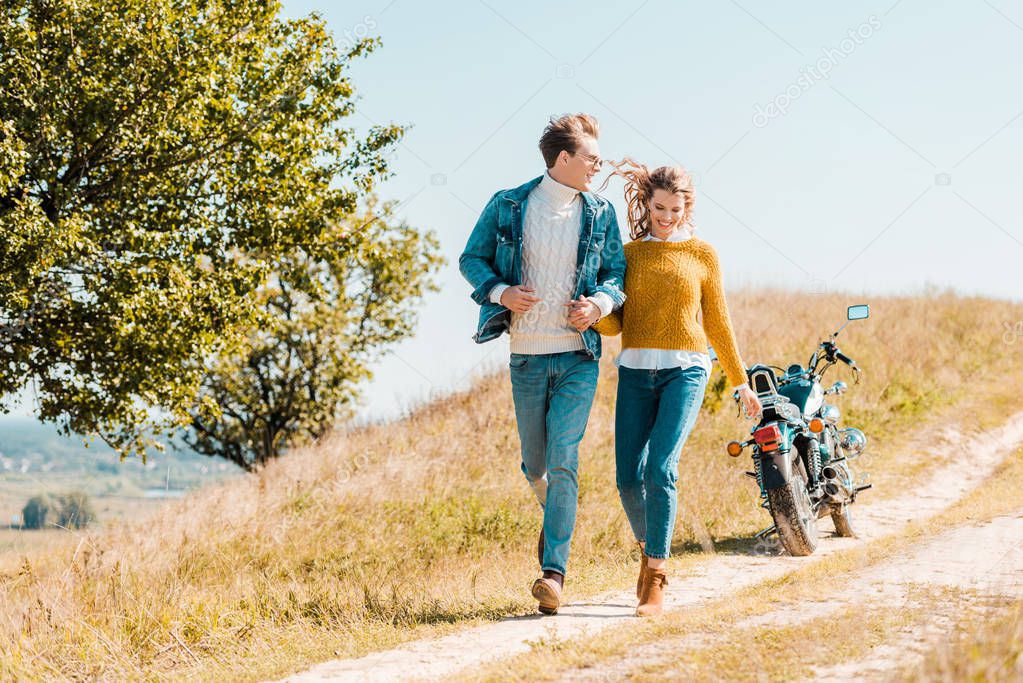 happy couple running on rural meadow with motorbike on background