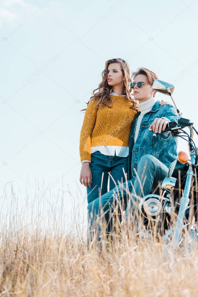 young couple standing near vintage motorbike