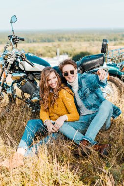 retro motosiklet yakınındaki gülümseyen çift oturma