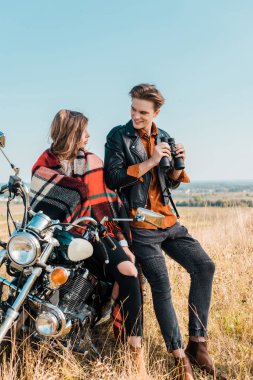 Dürbün tutarak ve motosiklet üzerinde oturan kız bakarak yakışıklı erkek 