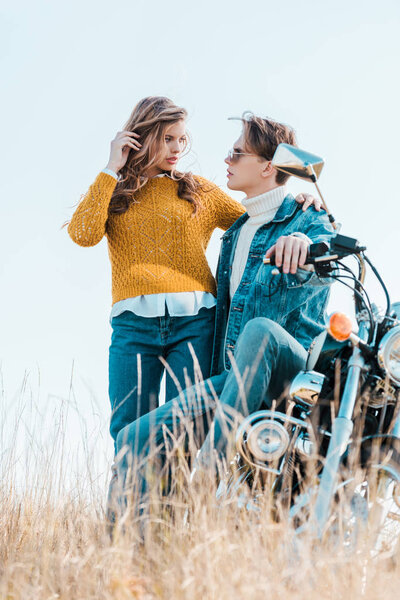 young couple looking at each other and standing near motorbike