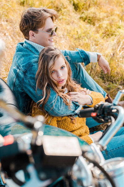 boyfriend hugging beautiful girlfriend and sitting on grass