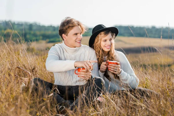 Leende Par Med Varma Drycker Tittar Bort Landsbygden Äng — Stockfoto