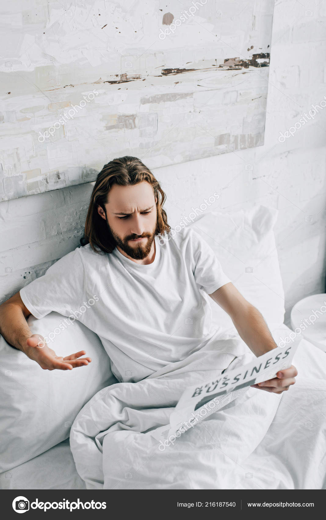 長い髪を手でベッドで読書新聞が 家で朝の時間の間に身振りで示すと感情的なひげを生やした実業家のハイアングル 無料のストック写真 C Vitalikradko