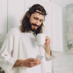 Foco seletivo de Jesus na coroa de espinhos de pé com xícara de café e usando smartphone na cozinha em casa