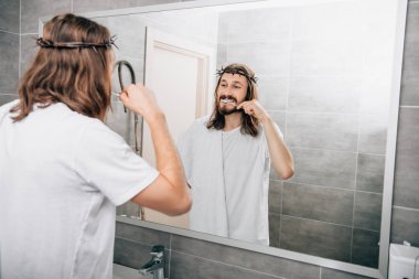 rear view of Jesus with towel over shoulder brushing teeth in bathroom  clipart