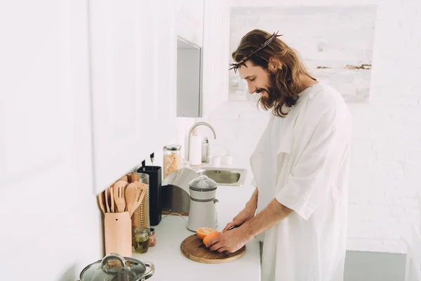 Lachende Jezus Snijden Orange Door Mes Houten Plank Keuken Thuis — Gratis stockfoto