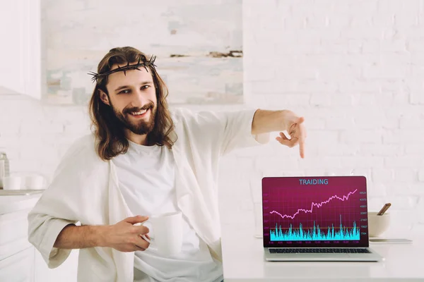 Sonriendo Jesús Sosteniendo Taza Café Señalando Computadora Portátil Con Comercio — Foto de Stock