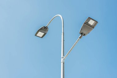 low angle view of street lamps against blue sky clipart