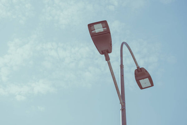 low angle view of street lamps against blue sky, toned image