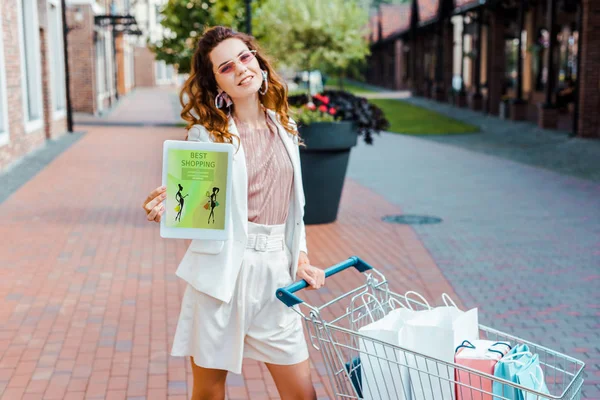 Beautiful Young Woman Shopping Cart Full Paper Bags Showing Tablet — Stock Photo, Image