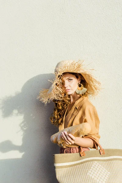 Fashionable Young Woman Straw Hat Baguette Standing Front White Wall — Free Stock Photo