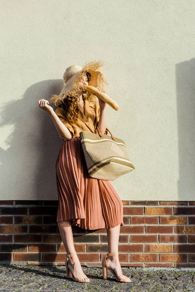 Attraente Donna Elegante Cappello Paglia Piedi Davanti Muro Bianco Mangiare — Foto stock gratuita