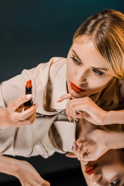 Retrato Mujer Elegante Mirando Lápiz Labial Rojo Mientras Apoya Superficie —  Fotos de Stock