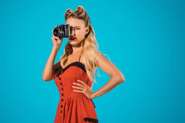 красивая женщина в ретро платье с фотокамерой изолированы на синий
