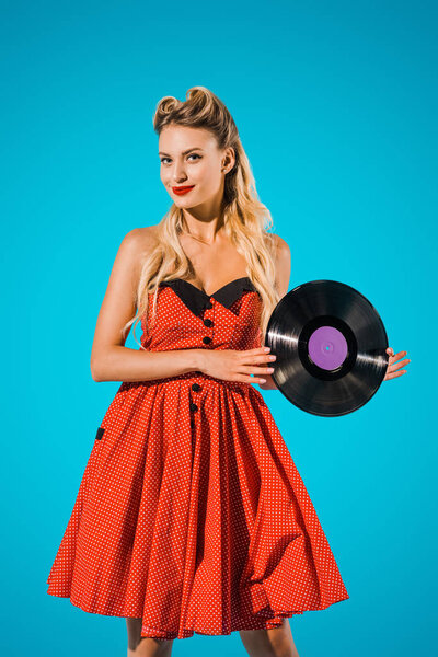 portrait of stylish woman in vintage dress with vinyl record on blue background