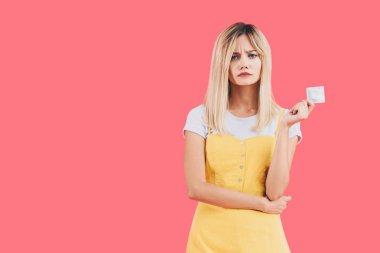 Pink izole prezervatif tutan duygusal genç şık kadın