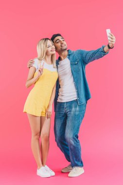 pink izole Smartphone cep telefonu ile barış işareti yapıyor kız arkadaşı ile selfie alarak yakışıklı genç 