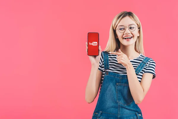 Portrait Smiling Woman Eyeglasses Pointing Smartphone Youtube Sign Isolated Pink — Stock Photo, Image