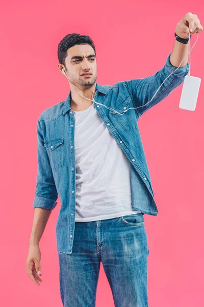 Retrato Homem Enojado Fones Ouvido Segurando Smartphone Isolado Rosa — Fotografia de Stock