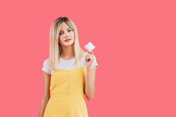 young stylish woman holding condom isolated on pink