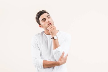 thoughtful young man with hand on chin looking away isolated on beige