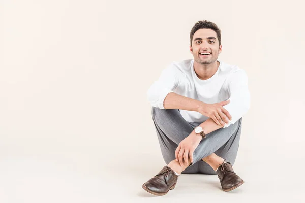 Jovem Alegre Sentado Sorrindo Para Câmera Isolada Bege — Fotografia de Stock