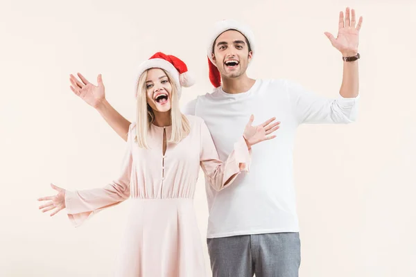 Vrolijke Jonge Paar Santa Hoeden Glimlachend Camera Geïsoleerd Beige — Gratis stockfoto