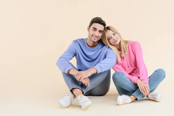 Mooie Gelukkige Jonge Paar Elkaar Zitten Lachend Camera Geïsoleerd Beige — Stockfoto