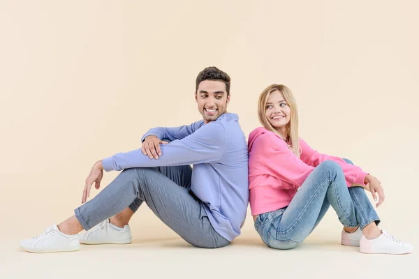 Boční Pohled Šťastný Mladý Pár Sedící Zády Sobě Izolované Béžové — Stock fotografie