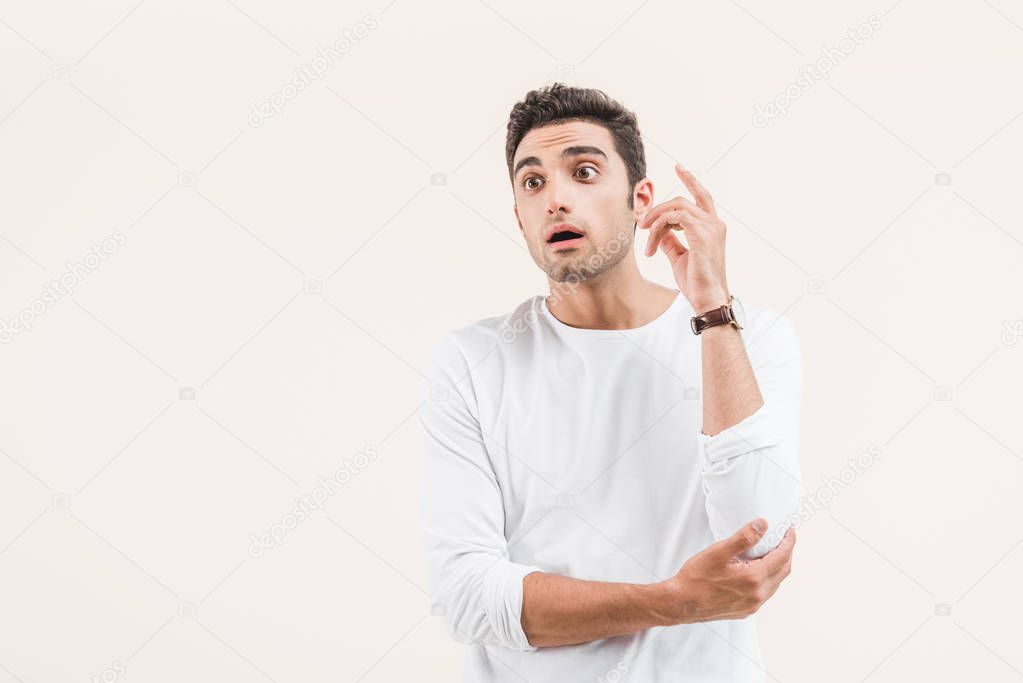 surprised young man with open mouth looking away isolated on beige