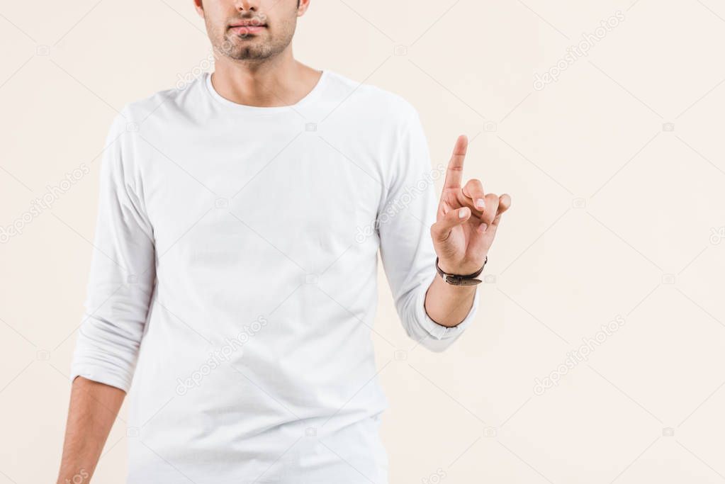 cropped shot of young man pointing up with finger isolated on beige